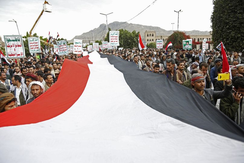 Les partisans des Houthis scandent des slogans en tenant des pancartes lisant