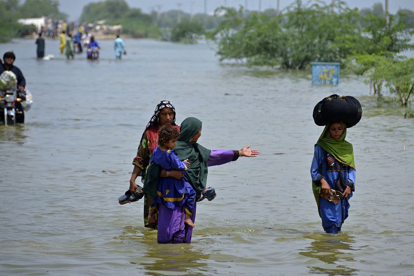 Des gens traversent les eaux de crue à Sohbatpur, un district de la province du Baloutchistan, au sud-ouest du Pakistan, le 29 août 2022.
