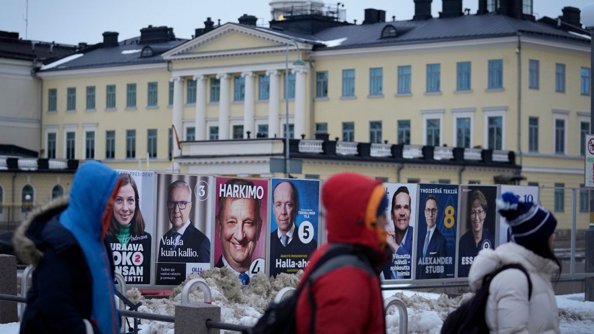 People walk by election posters with the Presidential Palace in the background, in Helsinki, Finland, Saturday, Jan. 27, 2024, ahead of the Finnish presidential election on Su