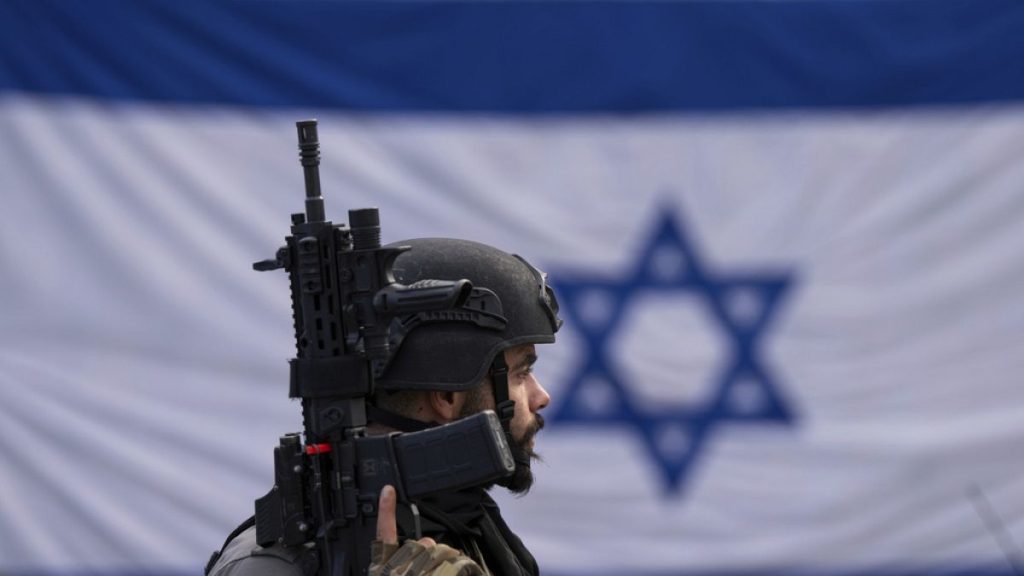 An Israeli border police officer stands guard at a bus stop in Ra