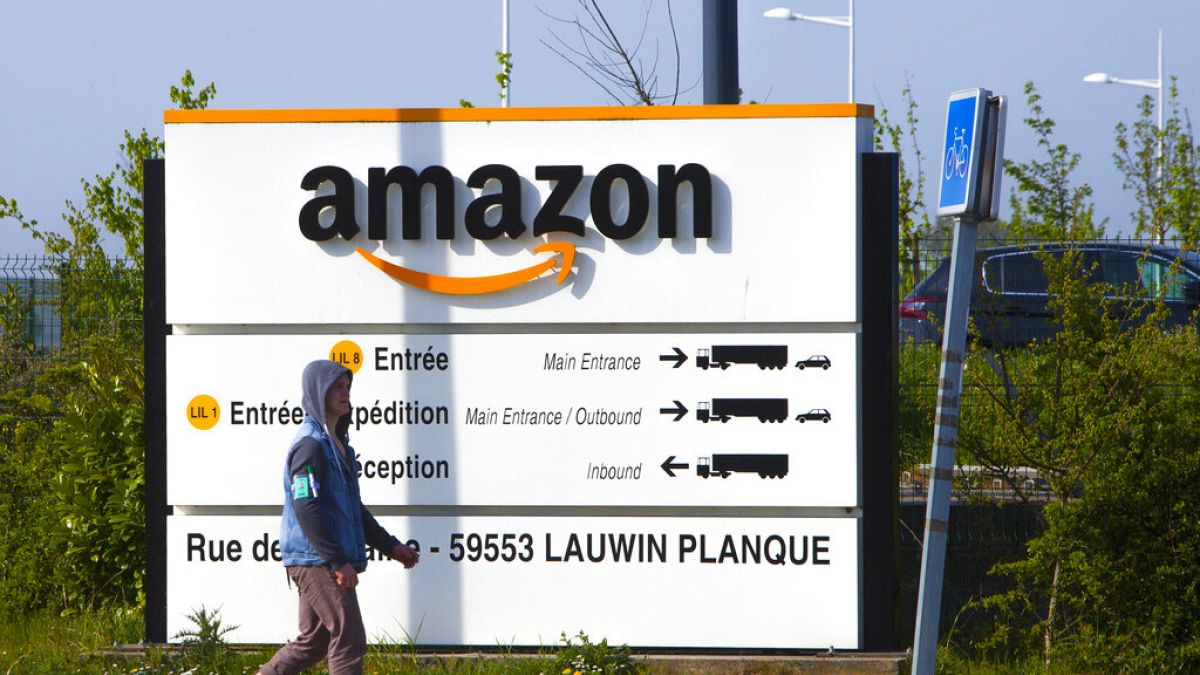 A man walks at the entrance of Amazon, in Douai, northern France, Thursday April 16, 2020.