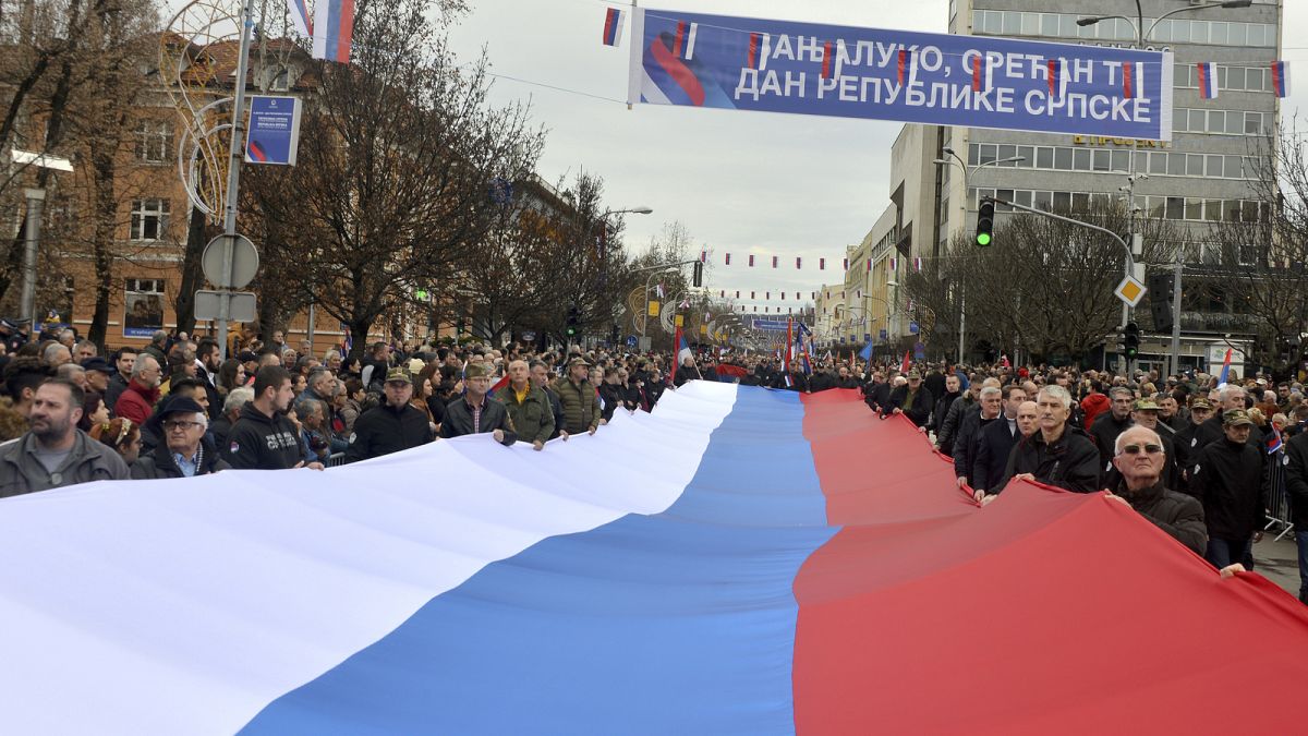 Bosnian Serbs march carrying a giant Serbian flag during a ceremony on the occasion of