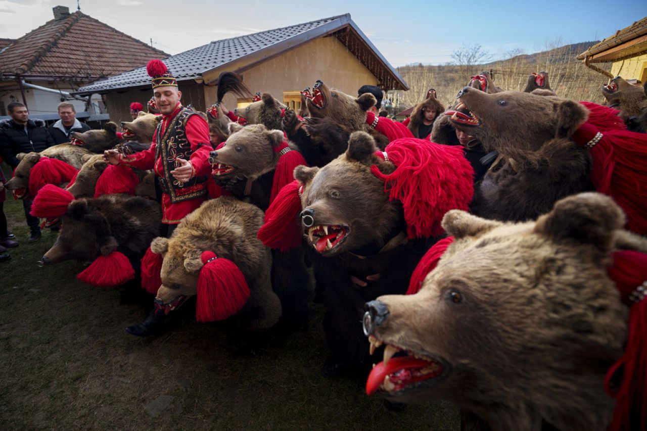 Les membres de la meute d'ours Sipoteni prennent la pose finale de leur performance à Preluci, dans le nord de la Roumanie, le 26 décembre 2023.