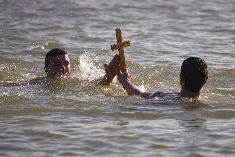 Des nageurs tiennent une croix en bois qu'ils ont récupérée dans le Danube lors des célébrations de l'Épiphanie à Facaieni, dans l'est de la Roumanie, le 6 janvier 2024.