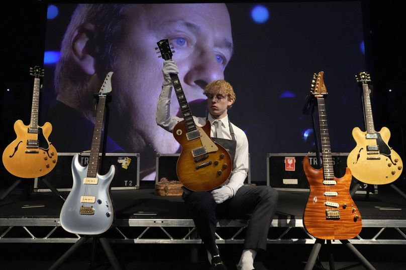 Un employé de Christie's montre une guitare Gibson Kalamazoo, entre autres, appartenant au chanteur, auteur-compositeur et guitar hero de Dire Straits, Mark Knopfler,