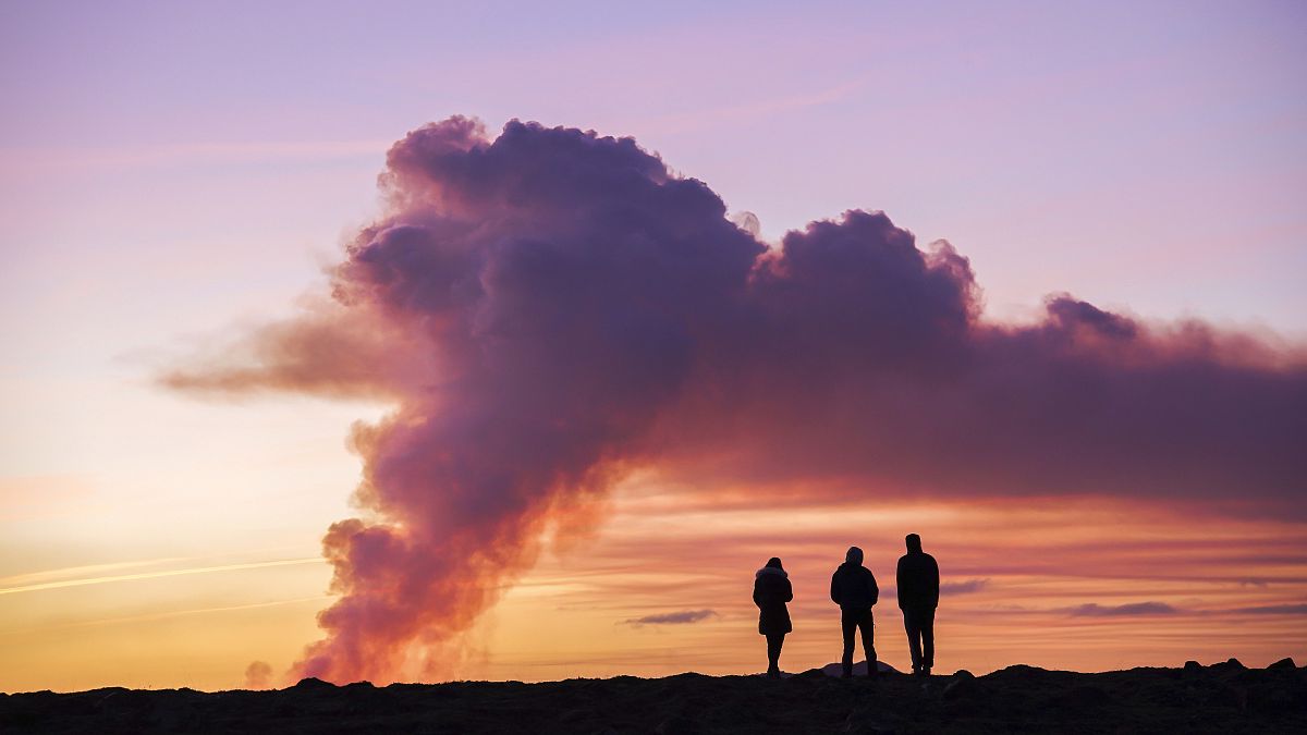 People observe the eruption from the nearby town of Grindavik, Iceland, on 14 January 2024