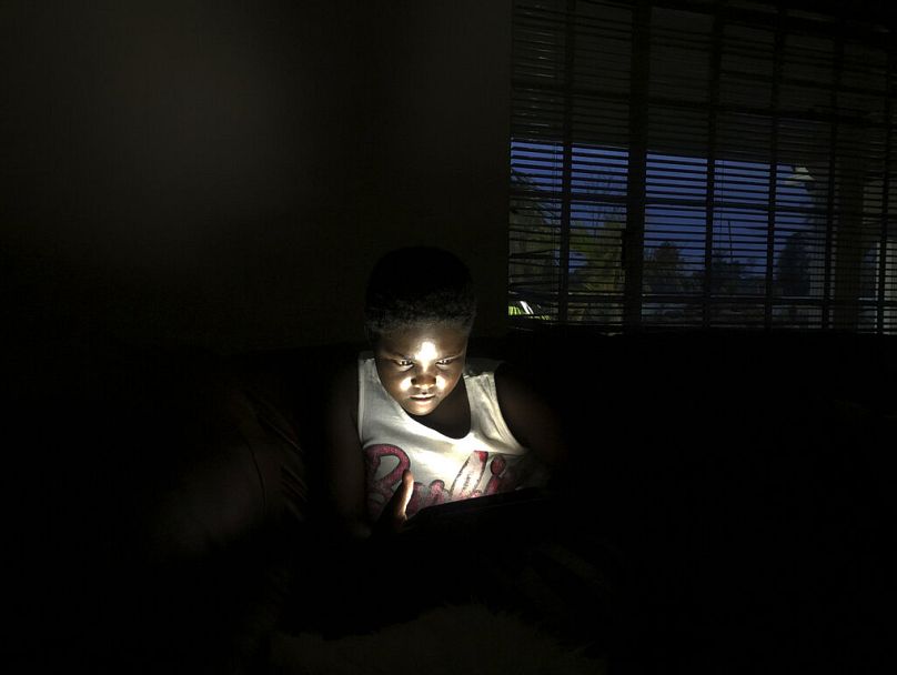Une jeune fille utilise son téléphone portable tout en le rechargeant à l'énergie solaire dans une maison à Harare, décembre 2019.