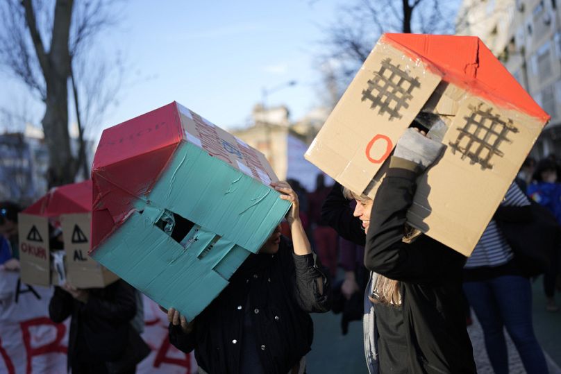 Des manifestants portent des maisons en carton au-dessus de leur tête lors d'une manifestation contre la crise du logement au Portugal, à Lisbonne, en janvier 2024.