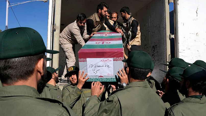 Des membres des Gardiens de la révolution déchargent le cercueil drapé d'un drapeau de l'une des victimes de l'attaque de mercredi revendiquée par l'EI.