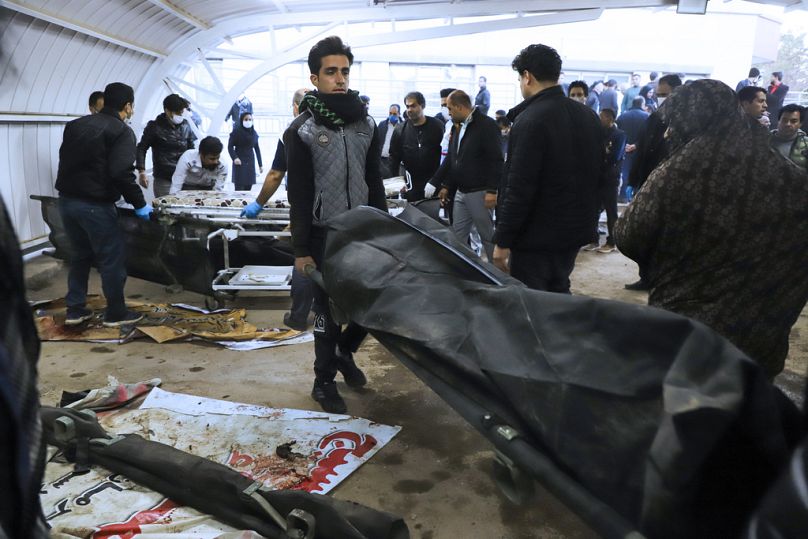 Un homme transporte le corps d'une victime dans un sac mortuaire suite à deux explosions dans la ville iranienne de Kerman.