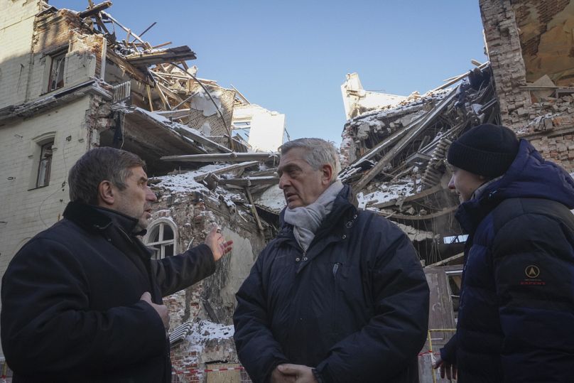Le Haut Commissaire des Nations Unies pour les réfugiés, Filippo Grandi, au centre, écoute un résident local alors qu'il visite les sites des récents attentats à la bombe à Kharkiv, en Ukraine, le lundi 22 janvier.