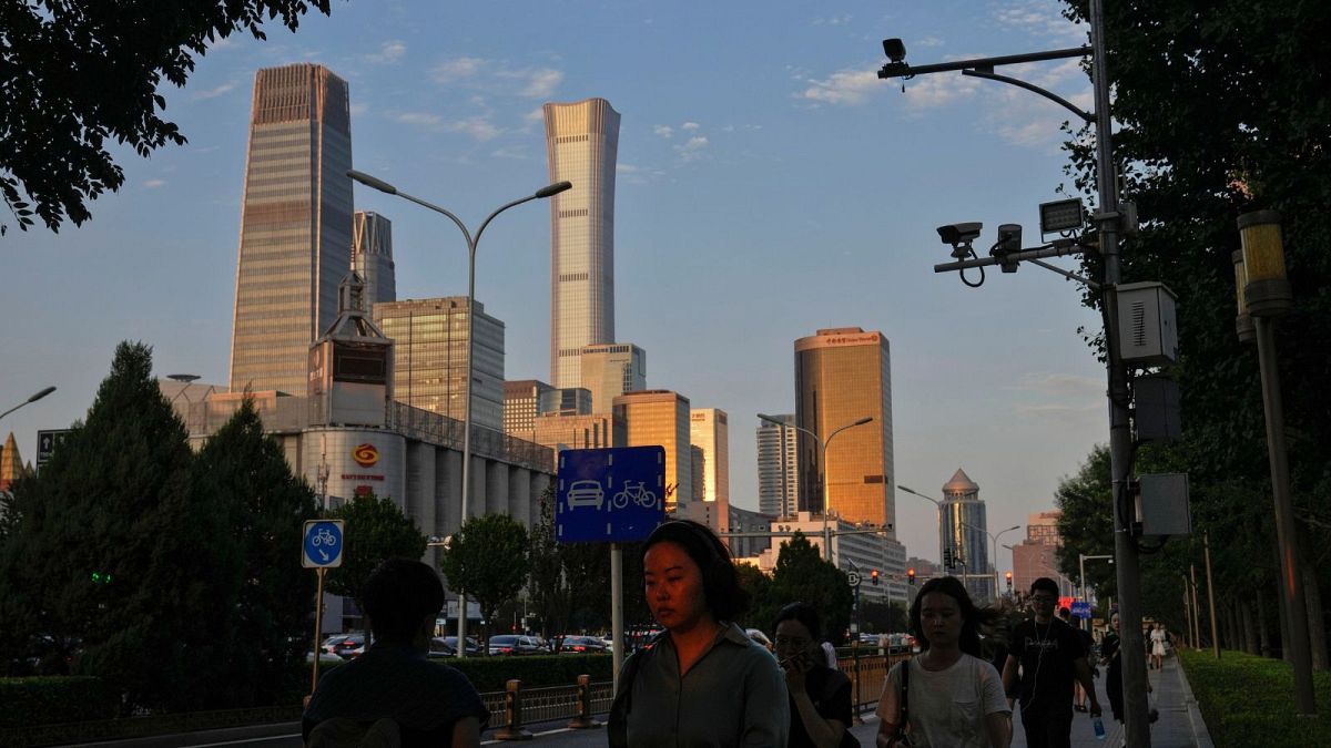 An evening sunlight casts on a woman as people walk near the Central Business District during the rush hour in Beijing on Monday, Aug. 14, 2023.