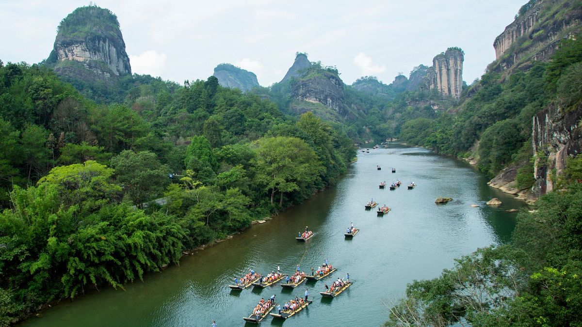 Tourists on bamboo rafts tour the Jiuqu river at a Wuyi mountain scenic area in southeast China