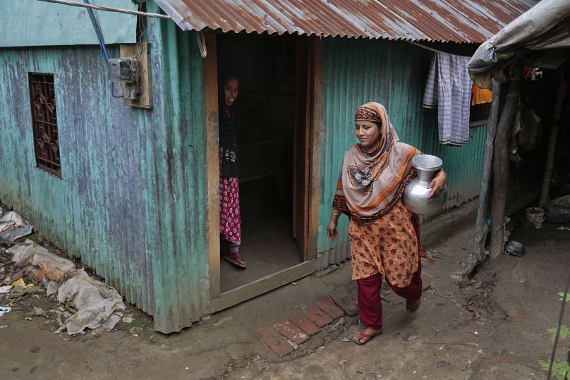 Une femme revient après avoir puisé de l'eau potable dans un puits tubulaire dans la banlieue de Dhaka, 2016.