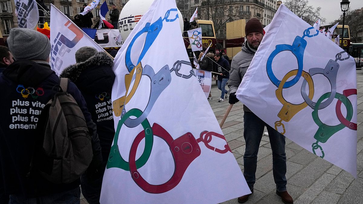 Police officers demonstrate with flags turning the olympic rings as handcuffs during a demonstration Wednesday, Jan. 10, 2024 in Paris.