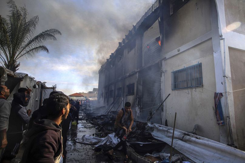 Des Palestiniens tentent d'éteindre un incendie dans un bâtiment d'un centre de formation professionnelle de l'UNRWA qui sert d'abri aux personnes déplacées, après avoir été pris pour cible par un char israélien.