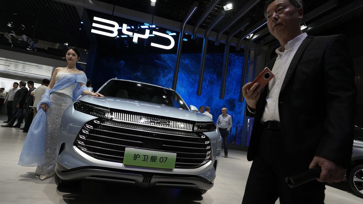 A model stands next to a car from BYD during the Shanghai auto show in Shanghai, on April 18, 2023.