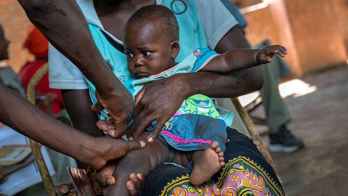 A baby from the Malawi village of Tomali is injected with the world