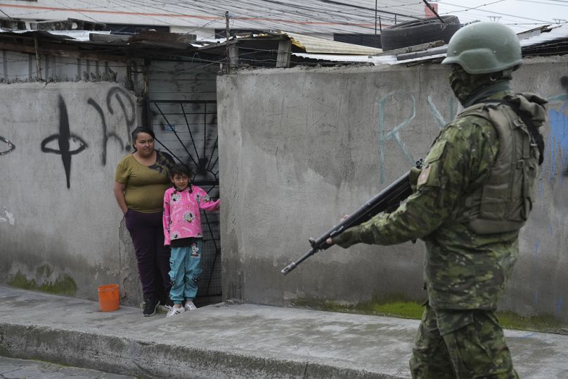Un soldat passe devant des habitants du sud de Quito, en Équateur, le vendredi 12 janvier 2024.