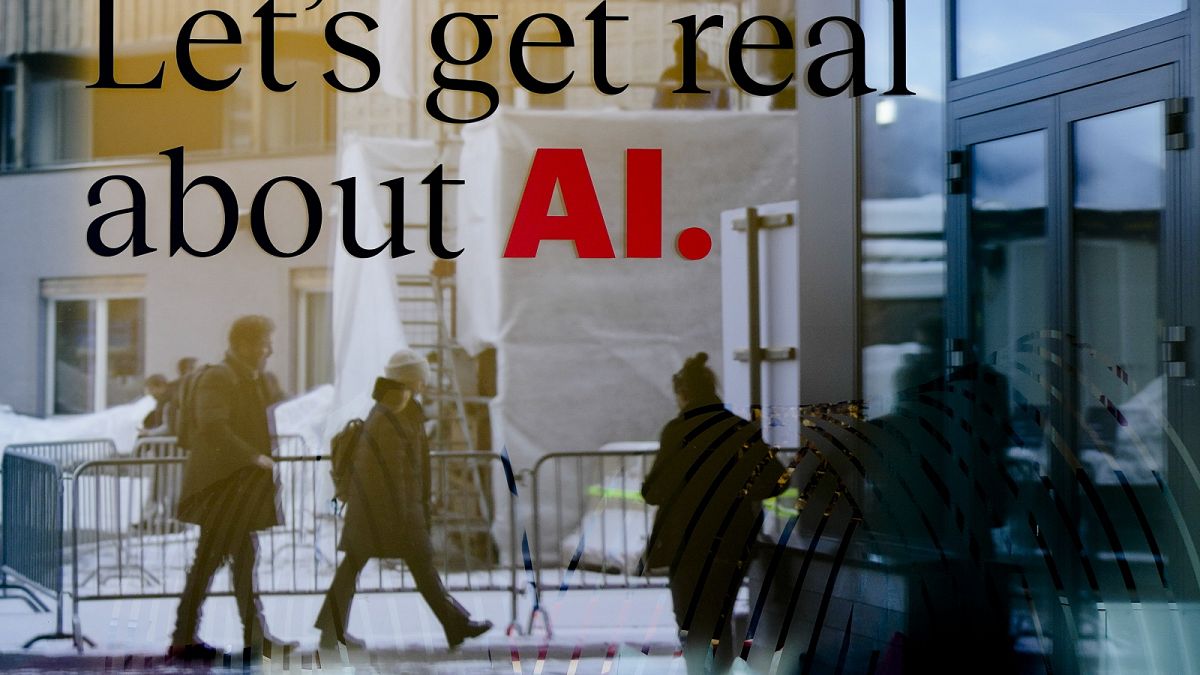 People reflected in a window of a hotel at the Davos Promenade with a slogan about AI alongside the World Economic Forum in Davos, Switzerland, Monday, January 15, 2024.