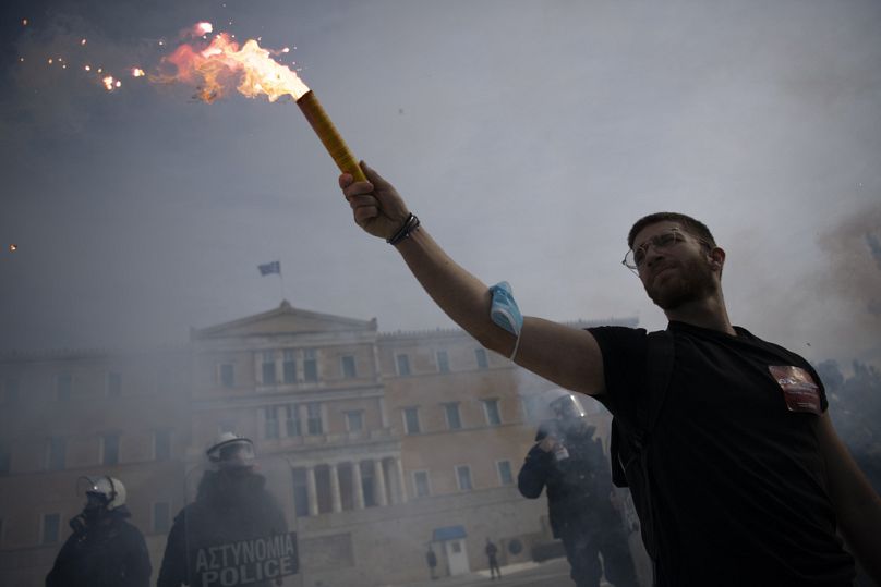 Un manifestant tient une fusée éclairante lors d'une manifestation devant le Parlement grec, à Athènes, en Grèce, le jeudi 18 janvier 2024.