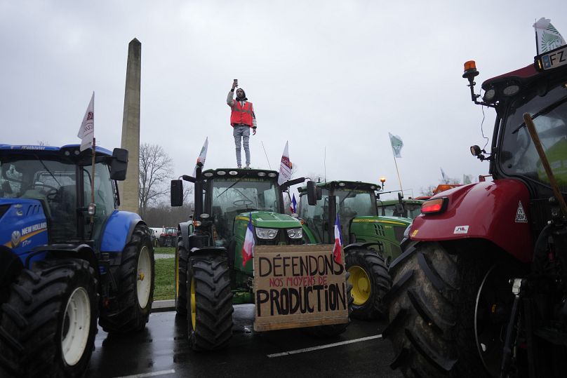 Un agriculteur se tient au sommet d'un tracteur alors qu'il bloque un rond-point à Fontainebleau, au sud de Paris.