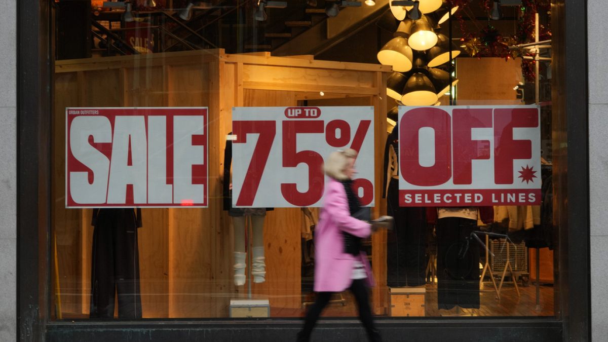 A shopper passes a window displaying a sale sign on Oxford Street in London, Wednesday, Dec. 20, 2023.