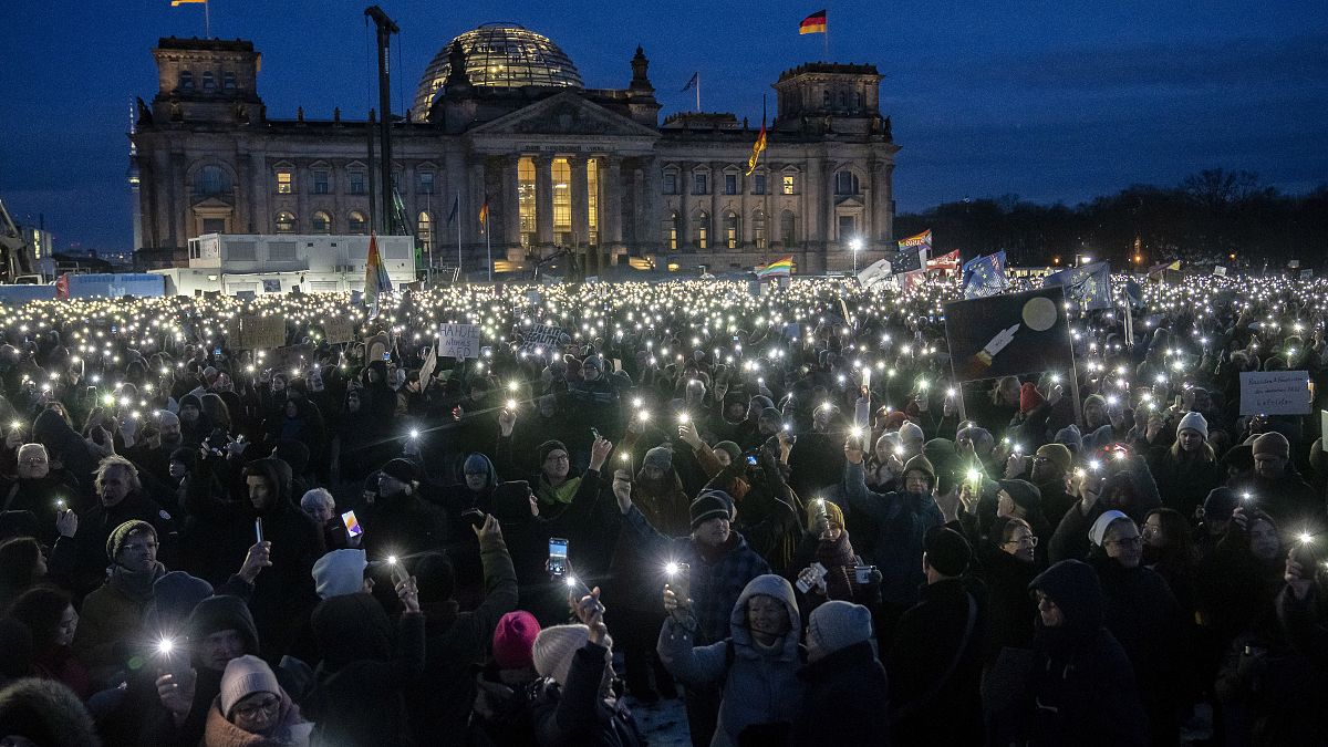 People hold up their cell phones as they protest against the AfD party and right-wing extremism in front of the Reichstag building in Berlin