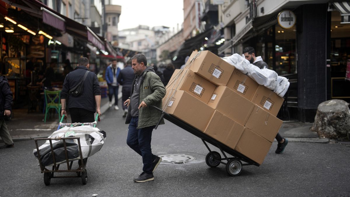 Two men pull trollies with goods in a street market in a commercial district in Istanbul, Turkey, Thursday, Dec. 21, 2023. Turkey