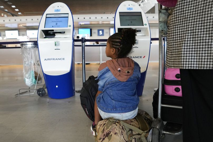 Les voyageurs attendent devant les comptoirs d'enregistrement vides de l'aéroport Roissy Charles de Gaulle, au nord de Paris.