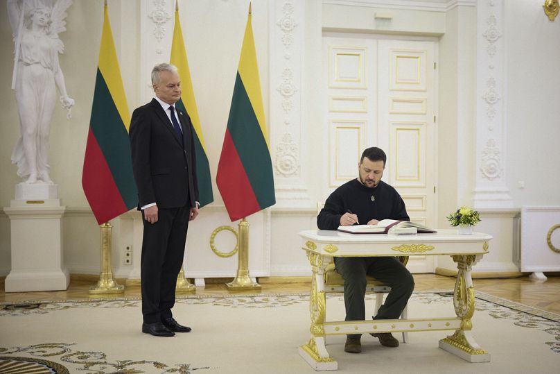 Le président lituanien Gitanas Nauseda, à gauche, regarde le président ukrainien Volodymyr Zelenskyy signer le livre d'or lors de leur réunion à Vilnius, en Lituanie.