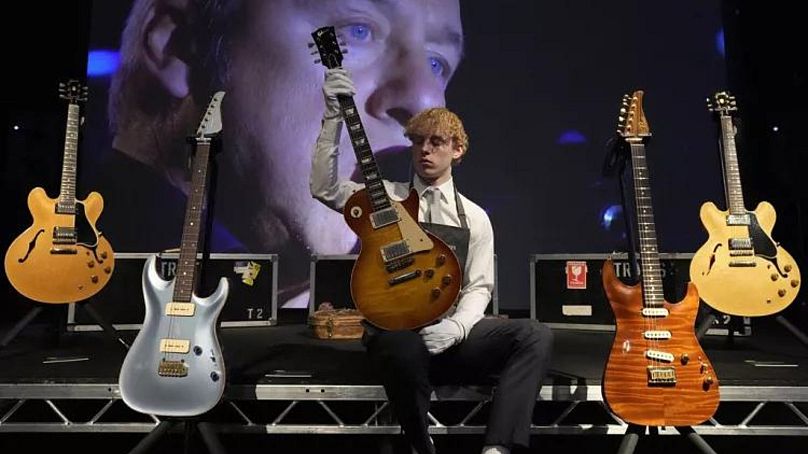 Un employé de Christie's montre entre autres une guitare Gibson Kalamazoo appartenant au chanteur/compositeur de Dire Straits Mark Knopfler