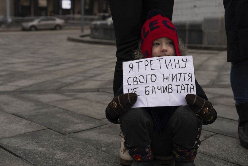 Matvii, 4 ans, tient une affiche en train de lire "Je n'ai pas vu mon père pendant un tiers de ma vie"alors qu'il assistait à un rassemblement sur la place de l'Indépendance à Kiev, janvier 2024