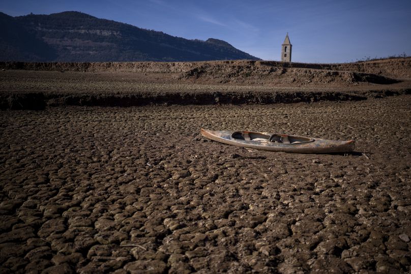 Un canot abandonné repose sur le sol fissuré du réservoir Sau.