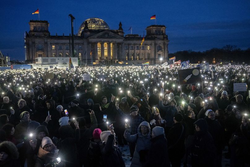 DOSSIER- Des gens brandissent leur téléphone portable alors qu'ils protestent contre le parti AfD et l'extrémisme de droite devant le bâtiment du Reichstag à Berlin, le 21 janvier 2024.