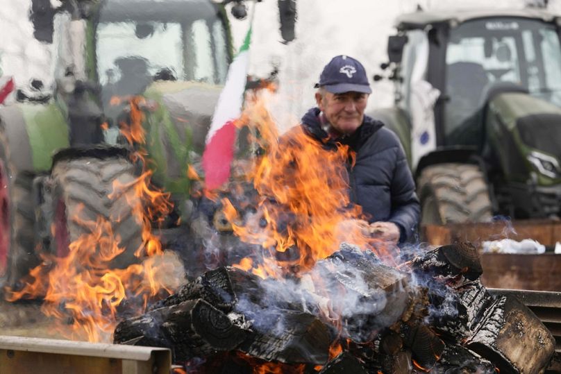 Un agriculteur est assis à côté d'un incendie lors d'un rassemblement près du carrefour autoroutier de Melegnano, près de Milan, février 2024.