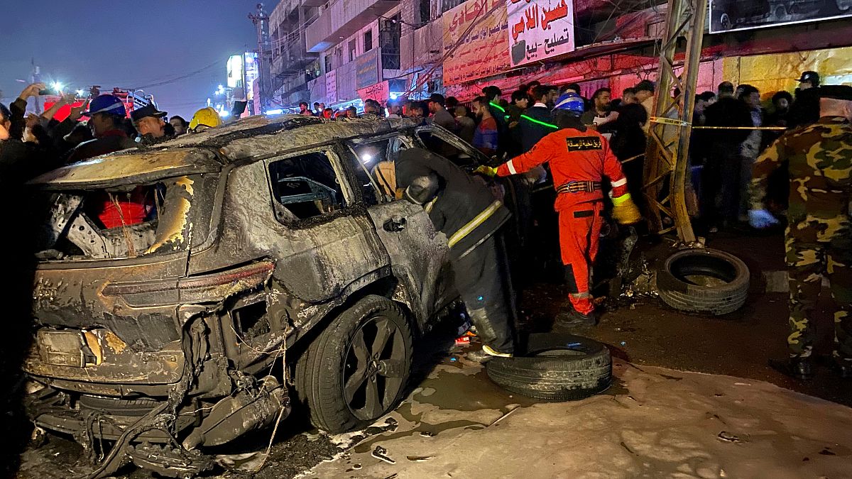 Civil defense members gather at the site of a burned vehicle targeted by a U.S. drone strike in east Baghdad, Iraq, Wednesday, Feb. 7, 2024.