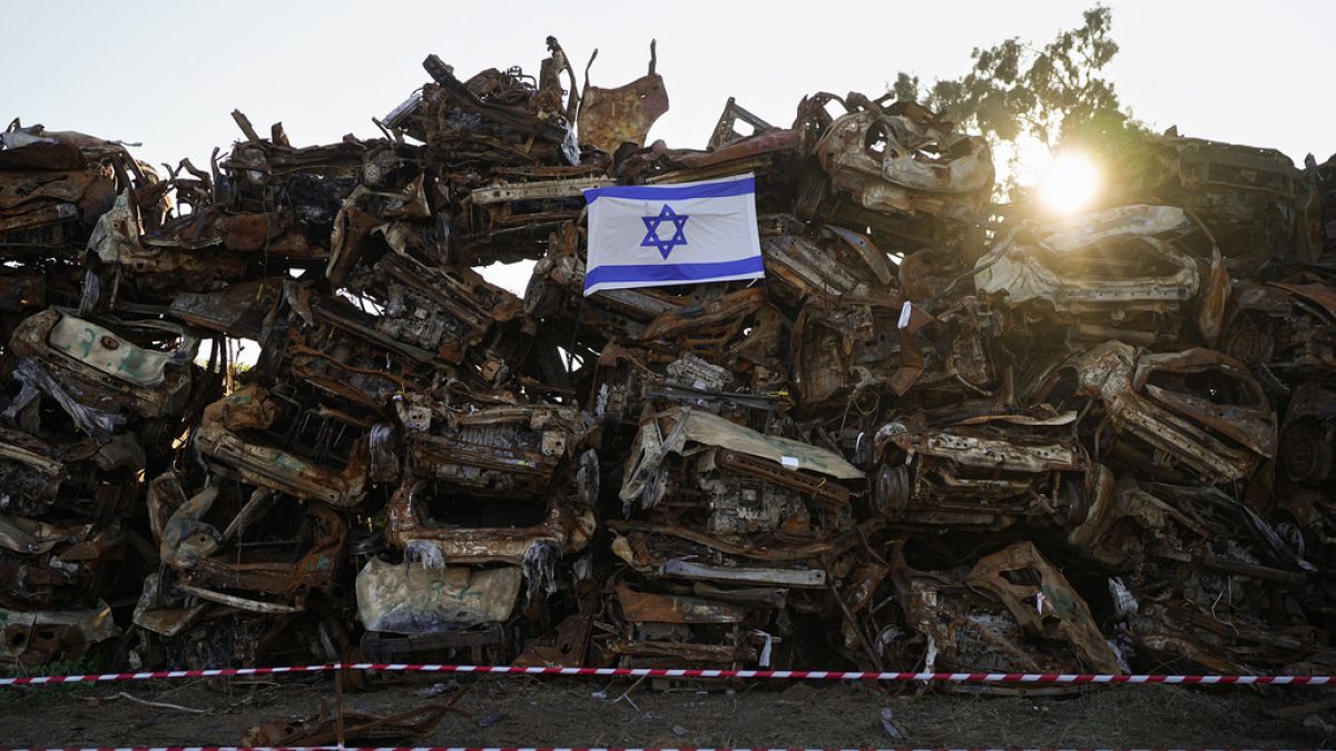 An Israeli flag is placed on a pile of charred vehicles burned in the bloody Oct. 7 cross-border attack by Hamas militants, outside the town of Netivot, southern Israel, 1/24.