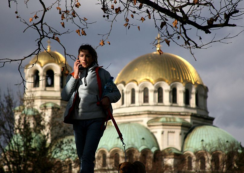 Photo d'archives d'une jeune fille bulgare passant devant la cathédrale Alexandre Nevski au dôme doré.