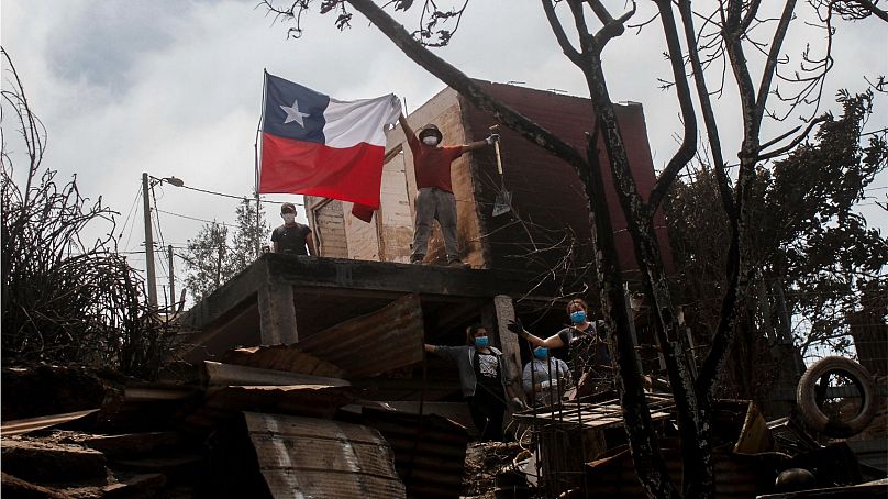 Un habitant pose et affiche un drapeau chilien depuis une maison incendiée après que des incendies de forêt ont atteint son quartier de Vina del Mar, au Chili, le dimanche 4 février 2024.