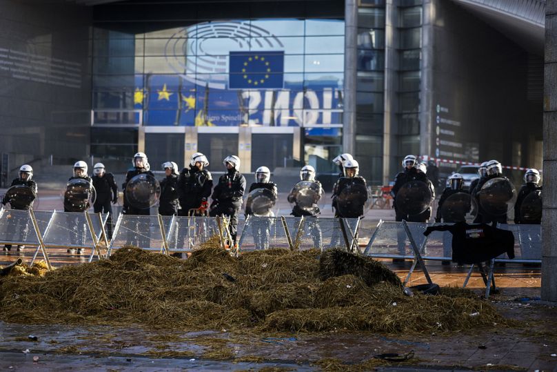 Des policiers anti-émeute montent la garde dans une zone de sécurité fermée devant le Parlement européen lors d'une manifestation d'agriculteurs alors que les dirigeants européens se réunissent pour un sommet européen.