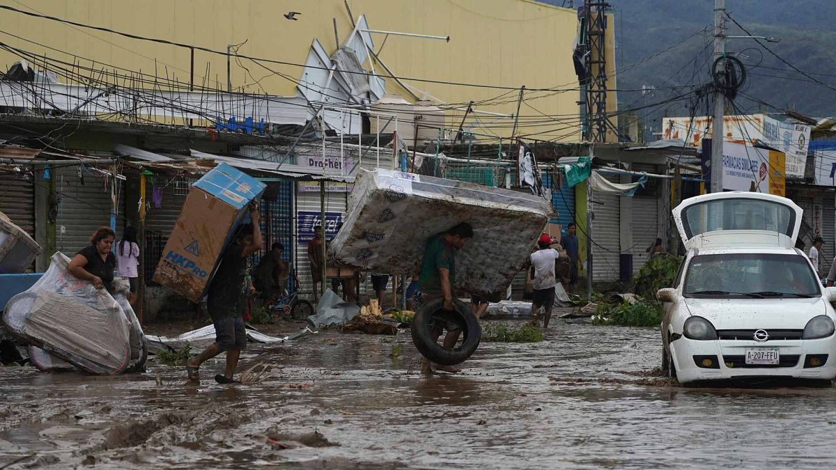 People carry away a mattress, a television monitor and a bicycle from a store at a shopping mall after Hurricane Otis ripped through Acapulco, Mexico, Oct. 25, 2023