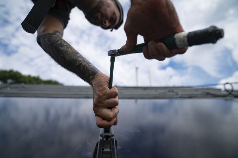 Un technicien installe une série de panneaux solaires sur un toit, août 2022