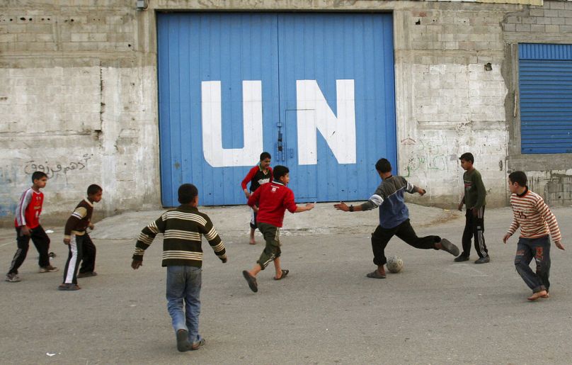 Des enfants palestiniens jouent au football devant la porte d'un centre de distribution alimentaire des Nations Unies dans la ville de Gaza, février 2009.