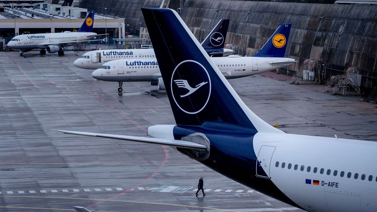 A person walks near parked Lufthansa aircrafts at the airport in Frankfurt, Germany, on 26 March 2023.