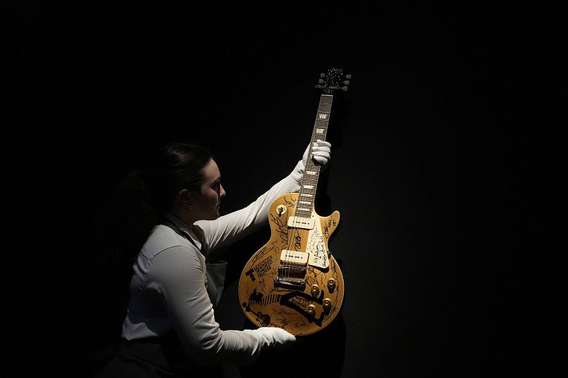 Un employé de Christie's vérifie une guitare Gibson Les Paul « Gold Top » appartenant à Mark Knopfler