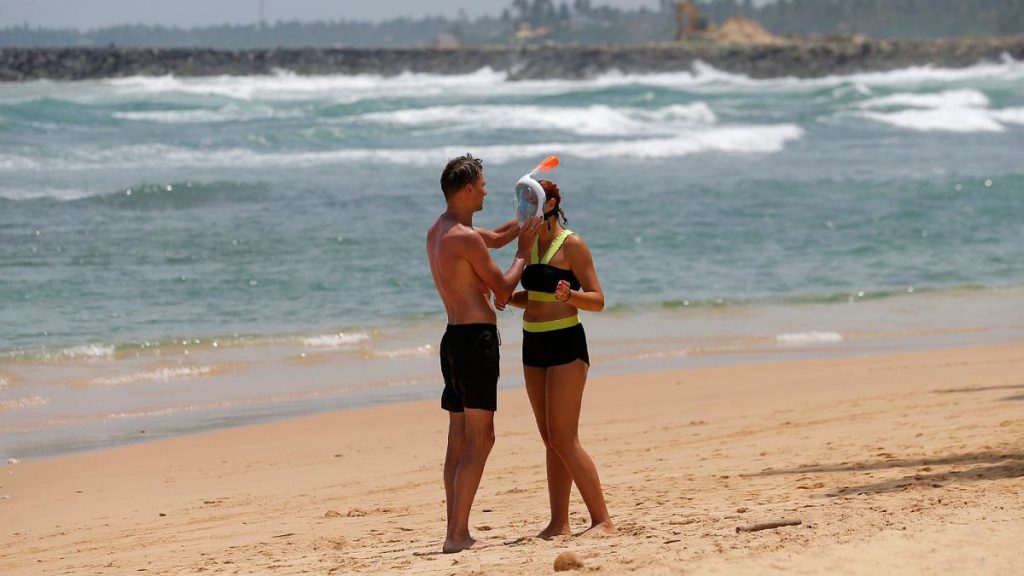 A Russian man helps a woman with a snorkel mask in Hikkaduwa, Sri Lanka.