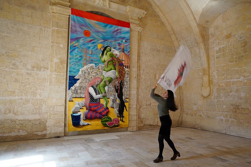 L'artiste italienne Teresa Antignani agite un drapeau devant sa peinture à l'huile « Depozione (Déposition) ». Elle a ajouté les pastèques comme symbole de la résistance palestinienne, a-t-elle déclaré.