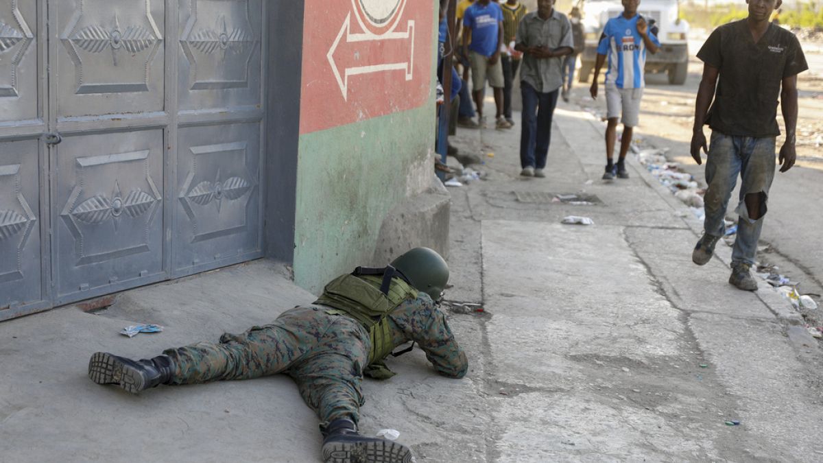 Pedestrians was past a soldier guarding the area of the international airport in Port-au-Prince, Haiti, Monday, March 4, 2024.