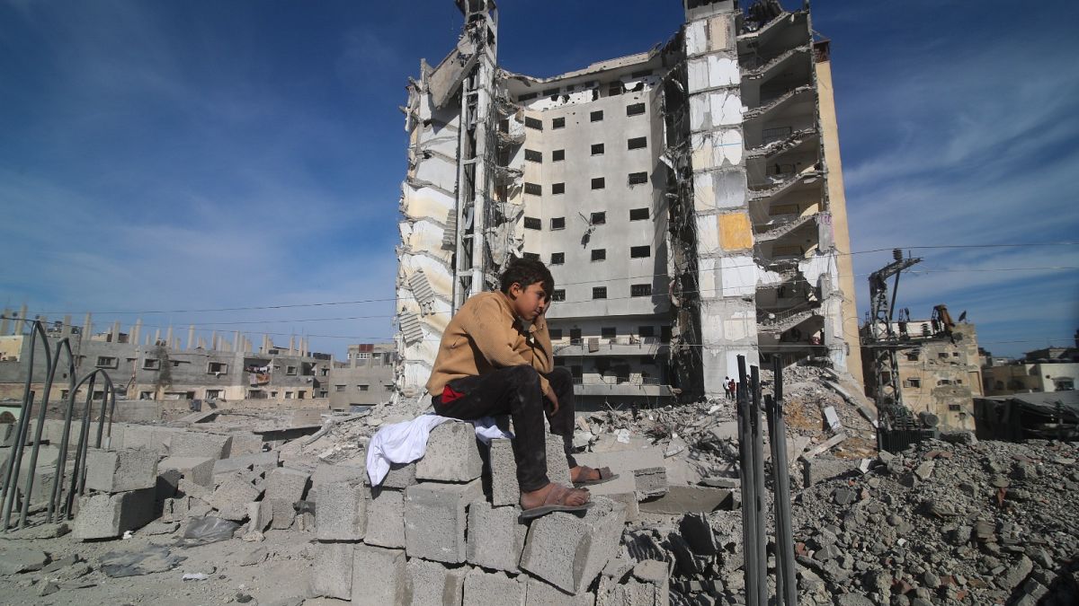 A Palestinian boy sits outside a residential building destroyed in an Israeli strike in Rafah, Gaza Strip, Saturday, March 9, 2024.